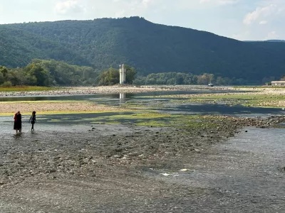 Due to low water level people walk over stones, which are usually covered by the Rhine river near the "Binger Maeuseturm" (Bingen Mouse Tower), Bingen, Germany, August 16, 2026, during prolonged dry weather across Europe that causes massive consequences for German industry.  REUTERS/Ilona Wissenbach   TPX IMAGES OF THE DAY / Foto: Ilona Wissenbach