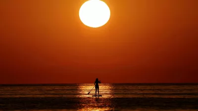 FILE PHOTO: A woman looks at the sunrise as she paddleboards on the Mediterranean Sea, in Barcelona, Spain July 2, 2025. REUTERS/Nacho Doce/File Photo