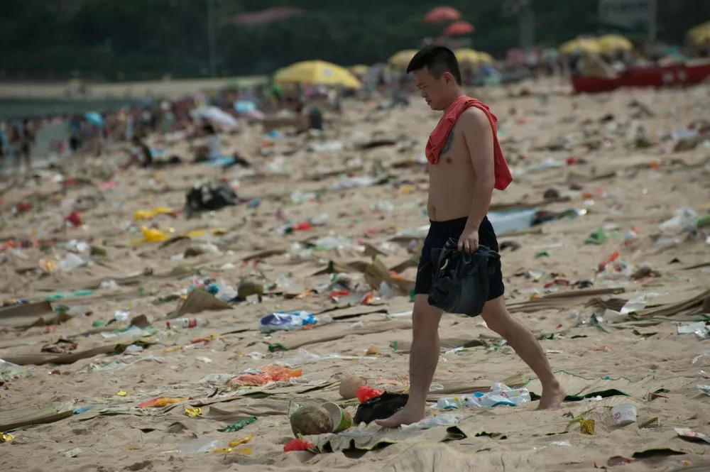 Tourists stay on the beach covered by garbage left by previous tourists in Shenzhen in south China's Guangdong province Tuesday June 3, 2014. Dameisha Beach Park received some 480,000 tourists in the past three days, who ruined the 160,000-square-meter beach with 362 tons of garbage.,Image: 195342829, License: Rights-managed, Restrictions:, Model Release: no 
