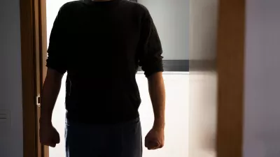 A dark room,a door opens with a silhouette of an unrecognisable man appears, he stands in the doorway and looks at his victim.Focus on shadow.