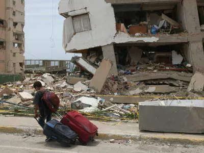 A child carries suitcases outside a Mision Vivienda housing building damaged by the June 24 earthquakes, in Catia la Mar, La Guaira state, Venezuela, July 9, 2026. REUTERS/Leonardo Fernandez Viloria / Foto: Leonardo Fernandez Viloria