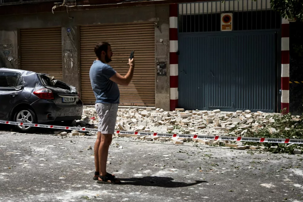 A passerby takes photographs of debris lying on the ground in the aftermath of an earthquake that struck southern Spain, in Granada, Spain, August 18, 2026. REUTERS/Fermin Rodriguez / Foto: Fermin Rodriguez