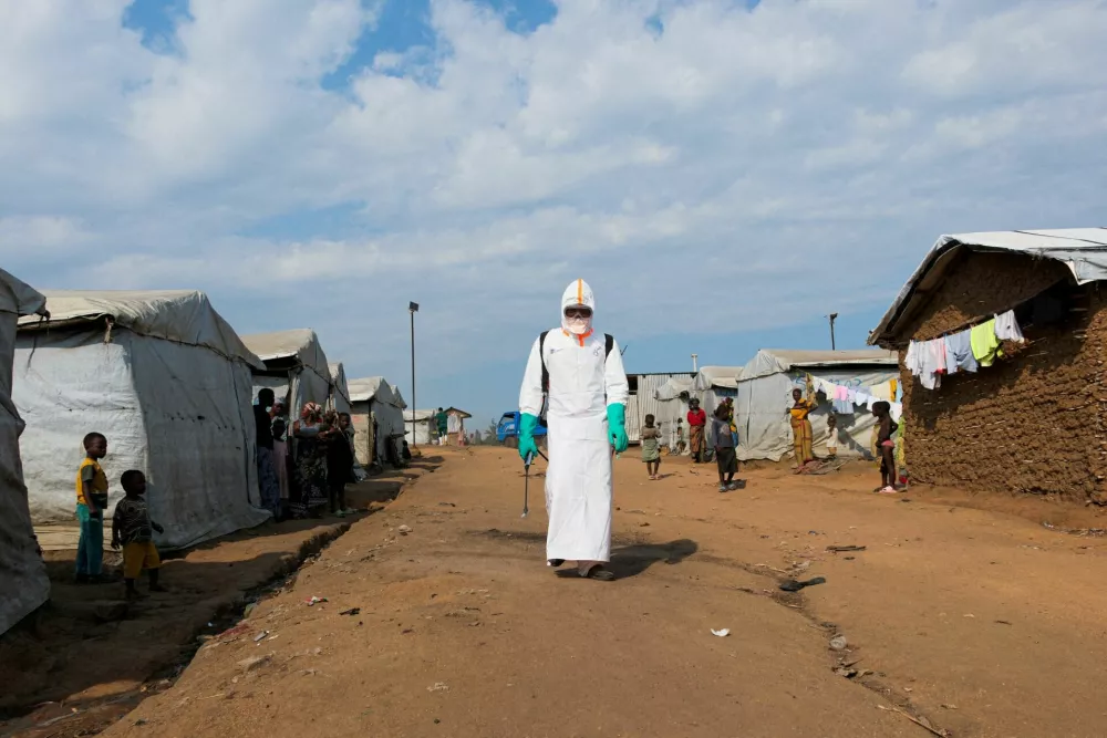 FILE PHOTO: Displaced people watch a health worker in full personal protective equipment (PPE) preparing to disinfect the area during the burial of suspected Ebola victims at the Kigonze displaced persons camp in Bunia, eastern Democratic Republic of Congo, on June 18, 2026, one month after the outbreak was declared. REUTERS/Gradel Muyisa Mumbere/File Photo / Foto: Gradel Muyisa Mumbere