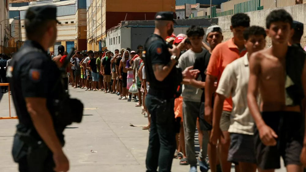 FILE PHOTO: Migrants queue to receive food staples from local NGO Media Luna Blanca in an industrial area where they are sleeping amid recent mass crossings by migrants on foot and by sea from Morocco into the Spanish territory, in Ceuta, Spain, August 6, 2026. REUTERS/Violeta Santos Moura/File Photo