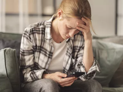 Woman reading some bad news on her smart phone, feeling sad and worried