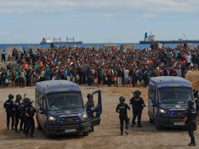 Migrants who crossed from Morocco into Spain return to a beach after being expelled from the area the previous day, as Spanish police escort them in the Spanish exclave of Ceuta, Friday, Aug. 21, 2026. (AP Photo/Antonio Sempere)