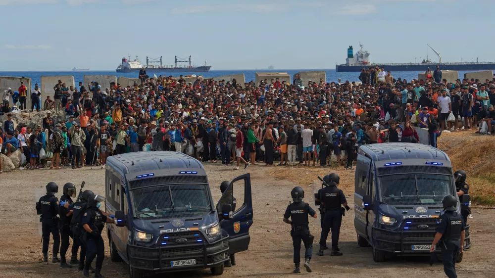 Migrants who crossed from Morocco into Spain return to a beach after being expelled from the area the previous day, as Spanish police escort them in the Spanish exclave of Ceuta, Friday, Aug. 21, 2026. (AP Photo/Antonio Sempere)