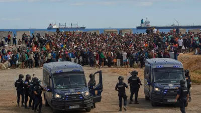 Migrants who crossed from Morocco into Spain return to a beach after being expelled from the area the previous day, as Spanish police escort them in the Spanish exclave of Ceuta, Friday, Aug. 21, 2026. (AP Photo/Antonio Sempere)