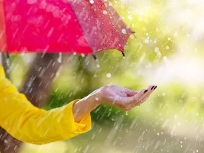 Woman standing outdoors with umbrella under the spring rain. Background and banner concept.