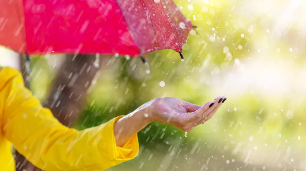 Woman standing outdoors with umbrella under the spring rain. Background and banner concept.