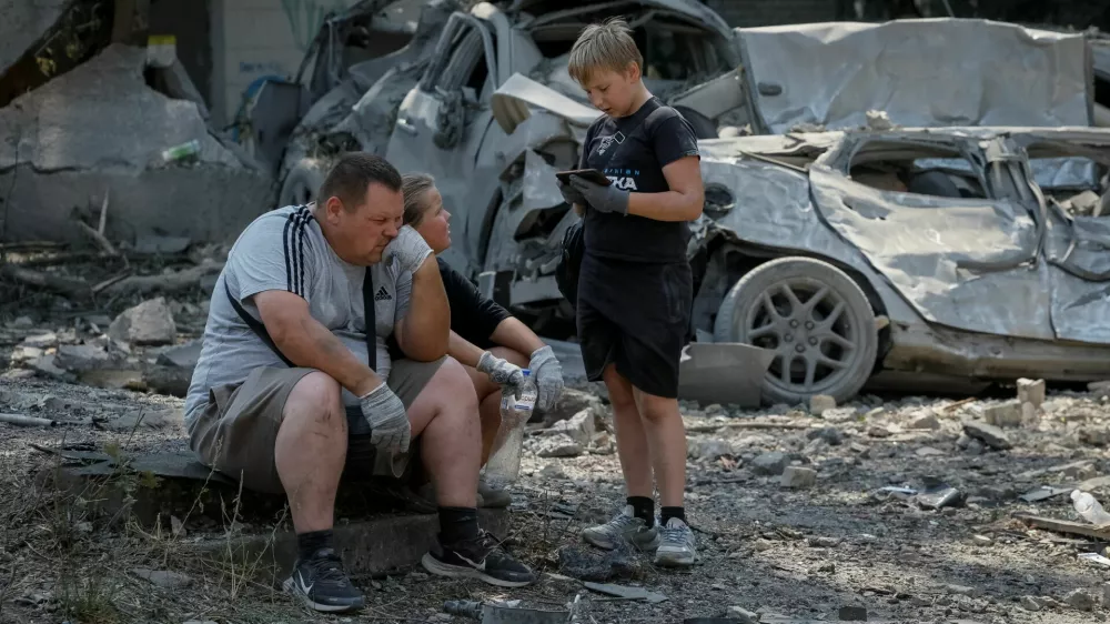A family waits for a tow truck near destroyed cars at the site of yesterday's missile strike, amid Russia's attack on Ukraine, in Kyiv, Ukraine, August 21, 2026. REUTERS/Gleb Garanich