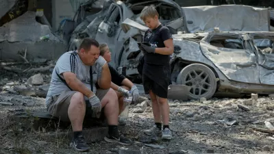 A family waits for a tow truck near destroyed cars at the site of yesterday's missile strike, amid Russia's attack on Ukraine, in Kyiv, Ukraine, August 21, 2026. REUTERS/Gleb Garanich