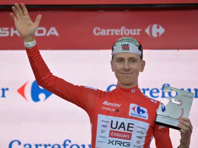 Slovenia's Tadej Pogacar, wearing the overall leader's red jersey celebrates on the podium after winning the first stage of the La Vuelta cycling race, a time trial with start and finish in Monaco, Saturday, Aug. 22, 2026. (AP Photo/Philippe Magoni)