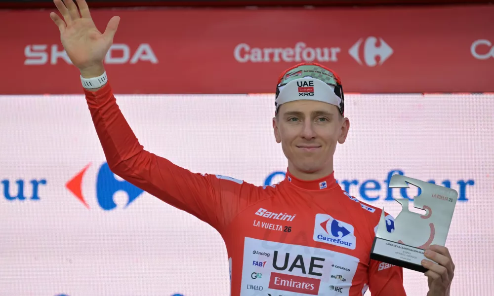Slovenia's Tadej Pogacar, wearing the overall leader's red jersey celebrates on the podium after winning the first stage of the La Vuelta cycling race, a time trial with start and finish in Monaco, Saturday, Aug. 22, 2026. (AP Photo/Philippe Magoni)
