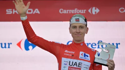 Slovenia's Tadej Pogacar, wearing the overall leader's red jersey celebrates on the podium after winning the first stage of the La Vuelta cycling race, a time trial with start and finish in Monaco, Saturday, Aug. 22, 2026. (AP Photo/Philippe Magoni)
