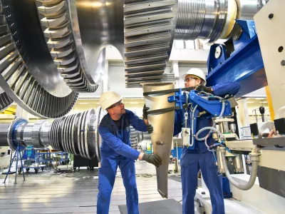 workers assembling and constructing gas turbines in a modern industrial factory