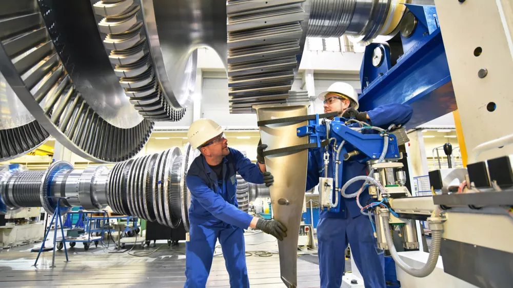 workers assembling and constructing gas turbines in a modern industrial factory