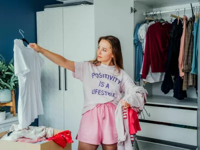 Woman selecting clothes from her wardrobe for donating to a Charity shop. Decluttering, Sorting clothes and Cleaning Up. Reuse, second-hand concept. Conscious consumer, sustainable lifestyle / Foto: Okrasyuk