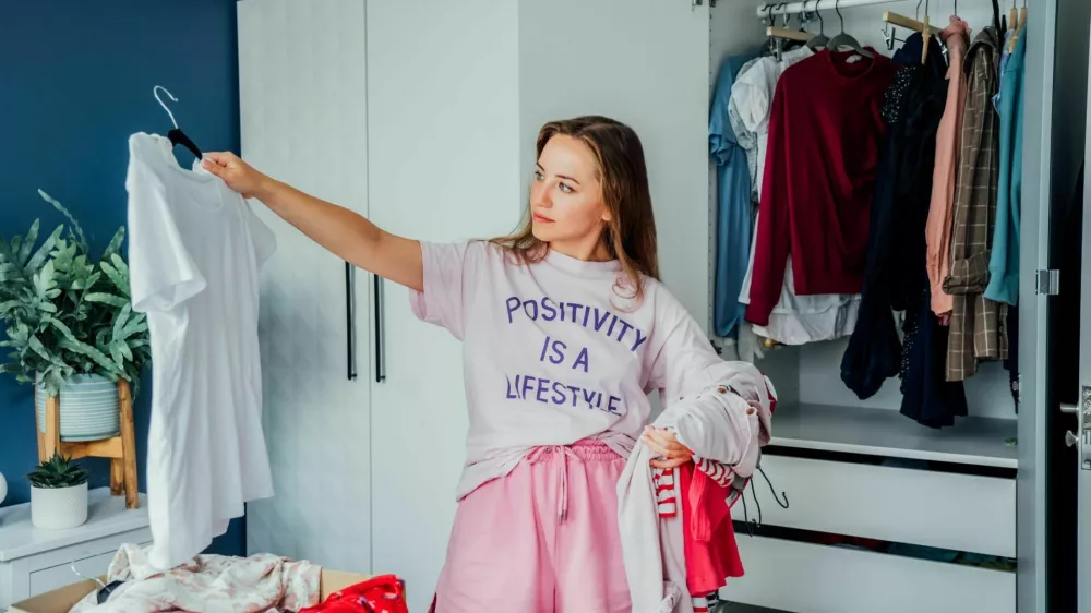 Woman selecting clothes from her wardrobe for donating to a Charity shop. Decluttering, Sorting clothes and Cleaning Up. Reuse, second-hand concept. Conscious consumer, sustainable lifestyle / Foto: Okrasyuk