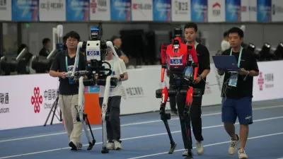 Technicians guide robots ahead of the 400m during the World Humanoid Robot Games in Beijing, Sunday, Aug. 23, 2026. (AP Photo/Achmad Ibrahim)