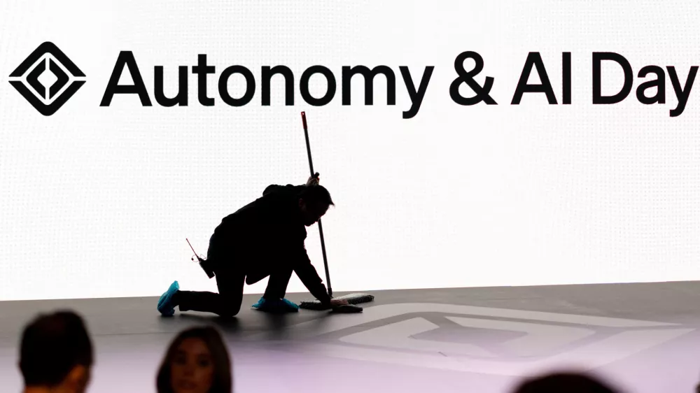 A man cleans a stage floor as attendees gather during Rivian's first Autonomy and AI (artificial intelligence) Day, showcasing developments in self-driving technology, in Palo Alto, California, U.S., December 11, 2025. REUTERS/Carlos Barria