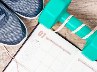 Calendar plan with green dumbbell and sneakers on wooden background. Workout plan concept. / Foto: Gam1983 Getty Images