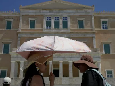 Tourists wearing hats visit the Tomb of the Unknown Soldier outside the Greek Parliament in Athens, Greece, Wednesday, Aug. 12, 2026. (AP Photo/Thanassis Stavrakis)