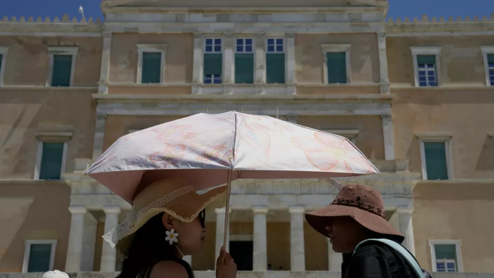 Tourists wearing hats visit the Tomb of the Unknown Soldier outside the Greek Parliament in Athens, Greece, Wednesday, Aug. 12, 2026. (AP Photo/Thanassis Stavrakis)