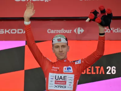 Slovenia's Tadej Pogacar, wearing the overall leader's red jersey celebrates on the podium after winning the first stage of the La Vuelta cycling race, a time trial with start and finish in Monaco, Saturday, Aug. 22, 2026. (AP Photo/Philippe Magoni)