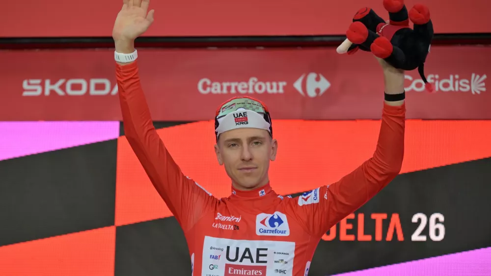 Slovenia's Tadej Pogacar, wearing the overall leader's red jersey celebrates on the podium after winning the first stage of the La Vuelta cycling race, a time trial with start and finish in Monaco, Saturday, Aug. 22, 2026. (AP Photo/Philippe Magoni)