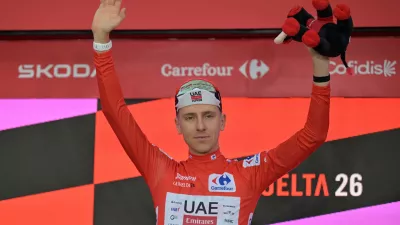 Slovenia's Tadej Pogacar, wearing the overall leader's red jersey celebrates on the podium after winning the first stage of the La Vuelta cycling race, a time trial with start and finish in Monaco, Saturday, Aug. 22, 2026. (AP Photo/Philippe Magoni)