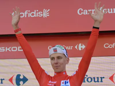Slovenia's Tadej Pogacar, wearing the overall leader's red jersey celebrates on the podium after the second stage of the La Vuelta cycling race, with start in Monaco and finish in Manosque, France, Sunday, Aug. 23, 2026. (AP Photo/Philippe Magoni)