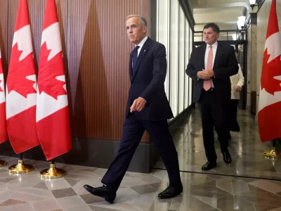 Prime Minister Mark Carney and Canada-U.S. Trade Minister Dominic LeBlanc arrive at a news conference about Canada's response to new U.S. tariffs on Parliament Hill in Ottawa on Saturday, Aug. 22, 2026. (Patrick Doyle/The Canadian Press via AP)