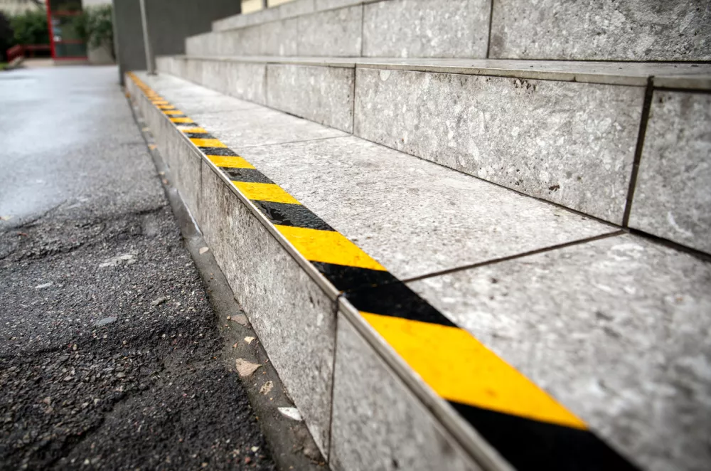 Yellow anti slip warning tape on stairs outdoors for safety. Public building / Foto: Edgars Sermulis Getty Images