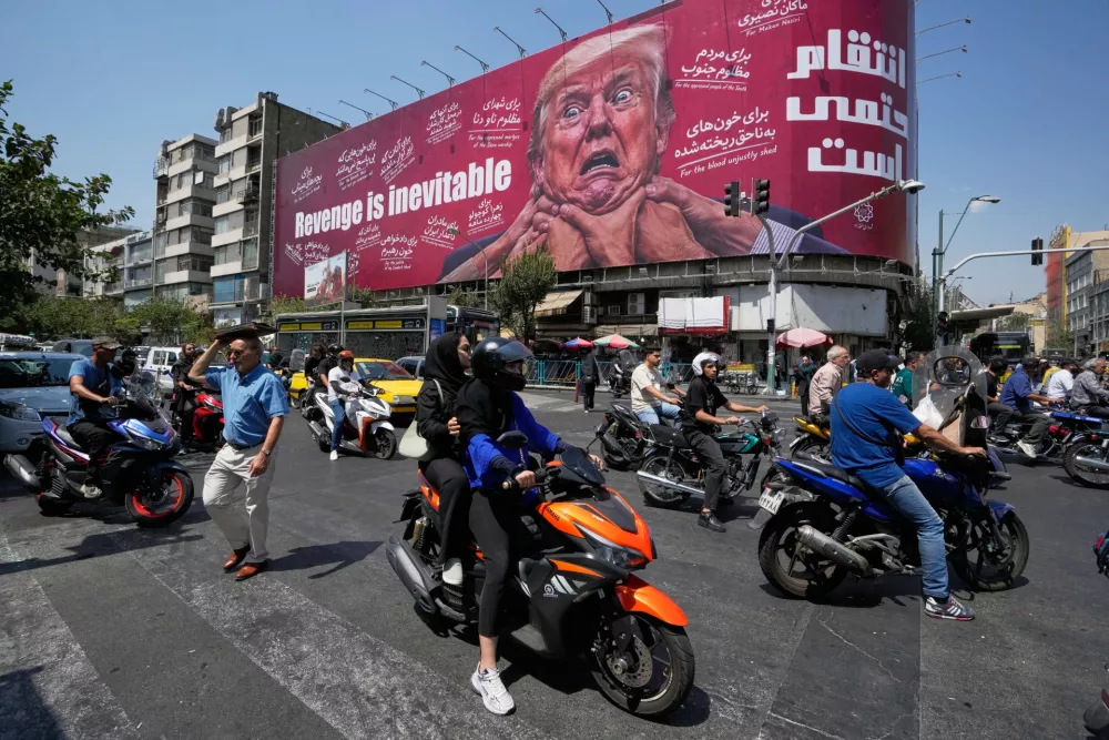 Motorcyclists pass a billboard depicting U.S. President Donald Trump with hands around his neck beneath the words "Revenge is inevitable" in Tehran, Iran, Monday, Aug. 24, 2026. (AP Photo/Vahid Salemi)
