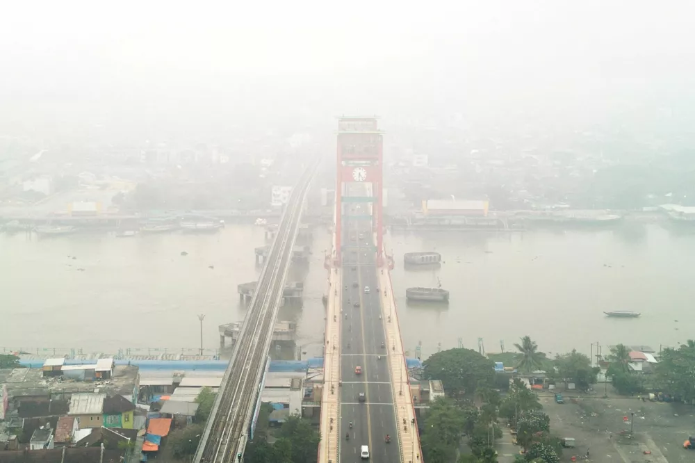 A drone view shows the Ampera Bridge shrouded in haze from wildfires in Palembang, South Sumatra province, Indonesia, August 25, 2026. REUTERS/Abriansyah Liberto