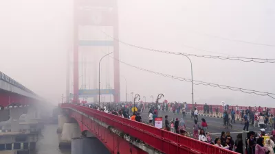 People walk along the Ampera Bridge as haze from wildfires blankets the city of Palembang, in South Sumatra, Indonesia, Sunday, Aug. 23, 2026. (AP Photo/Muhammad Fajri)