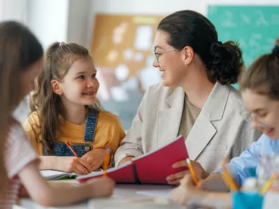 Happy kids and teacher at school. Woman and children are working in the class.