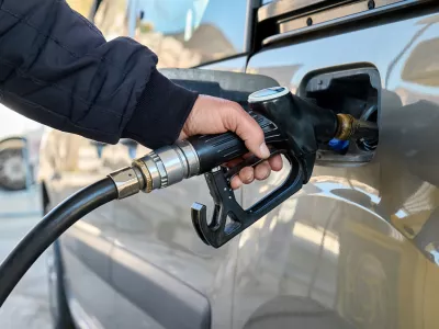 Hand of man driver holding fuel pump and refilling gasoline tank of car with fuel at gas station.