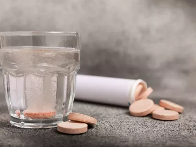 Effervescent tablet in a glass of water on a textured background. Vitamins. Health concept. Immunity drug. Space for copy. Space for text.