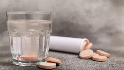 Effervescent tablet in a glass of water on a textured background. Vitamins. Health concept. Immunity drug. Space for copy. Space for text.