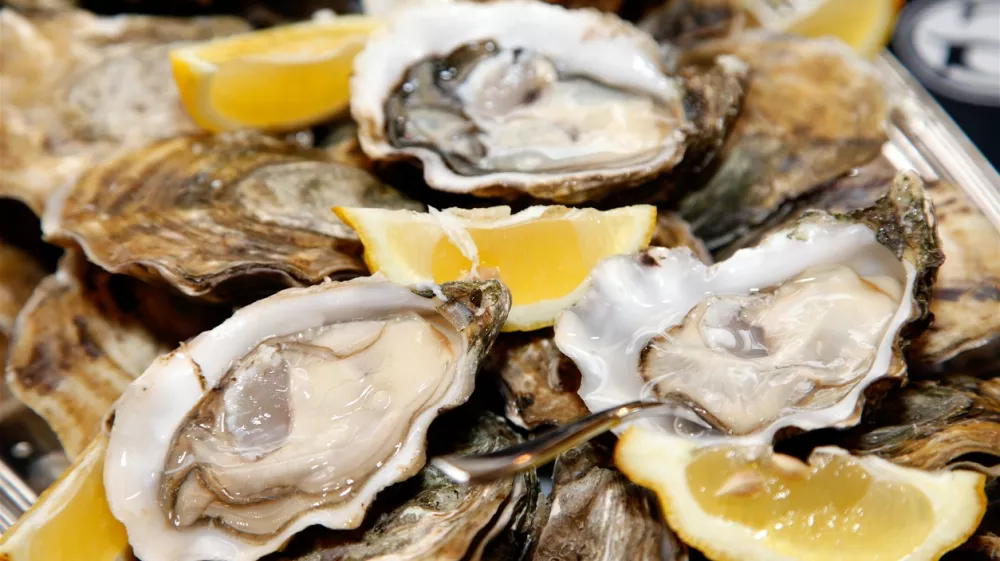 Close up of a platter of oysters with lemon wedges