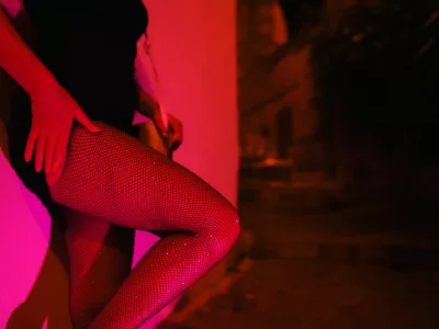 Woman in fishnet stockings waiting at night street