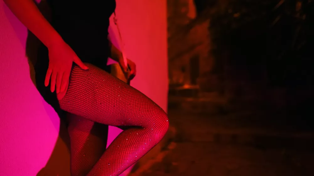 Woman in fishnet stockings waiting at night street