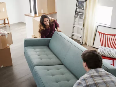Couple Surrounded By Boxes Carrying Sofa Into New Home On Moving Day / Foto: Monkeybusinessimages 