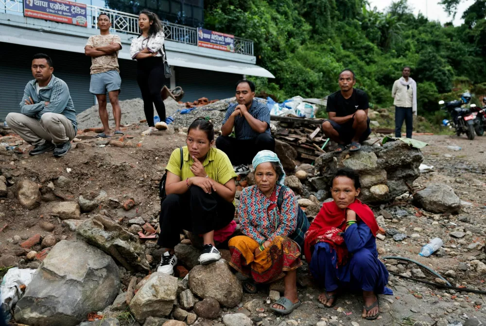 Survivors sit on debris as they wait for roads to clear to their homes following devastating floods in Trishuli, Nuwakot district, Nepal, August 27, 2026. REUTERS/Navesh Chitrakar