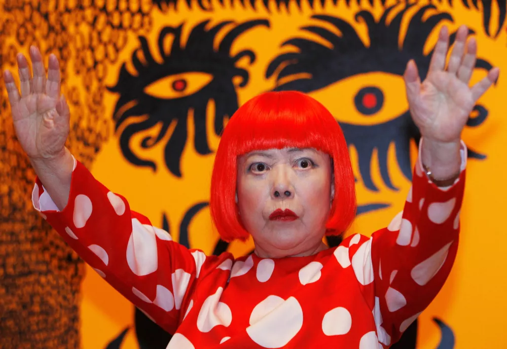 FILE PHOTO: Artist Yayoi Kusama poses for a photograph with a detail from her artwork "Love arrives at the Earth Carrying with it a Tale of the Cosmos" at the Tate Modern gallery in London, Britain, February 7, 2012.  REUTERS/Luke MacGregor/File Photo