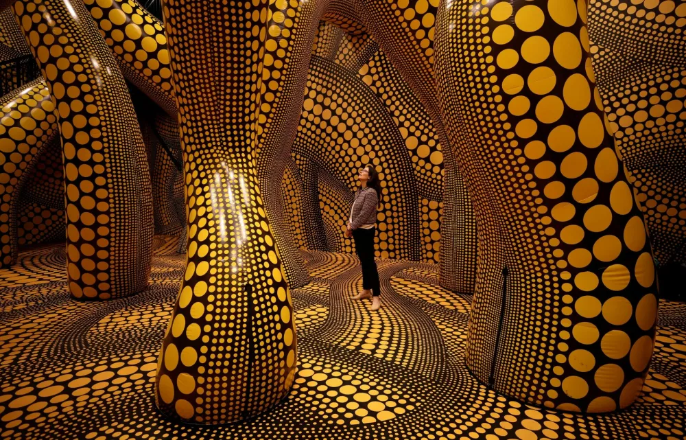FILE PHOTO: A visitor walks through a part of Japanese artist Yayoi Kusama's installation "You, Me and The Balloons" during a preview ahead of the start of the Manchester International Festival in Manchester, Britain, June 29, 2023. REUTERS/Phil Noble/File Photo