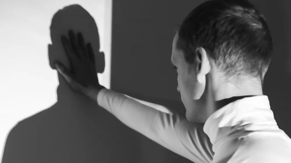 Man back view, touching his shadow on the wall, photo in black and white