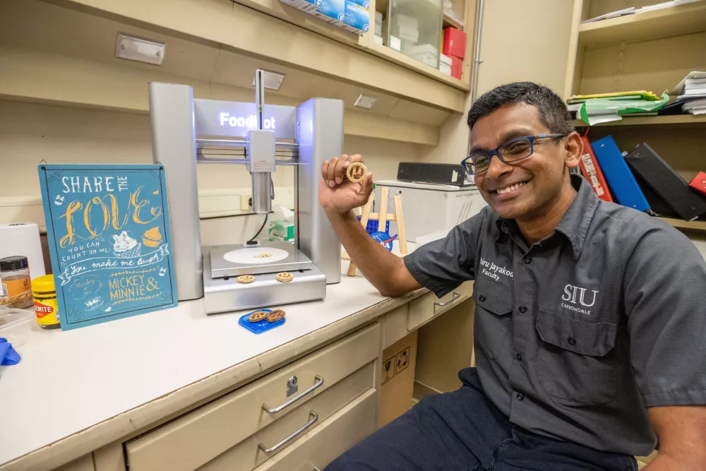 Mikrobiolog Lahiru Jayakody ob 3D-tiskalniku za hrano, s katerim njegova ekipa izdeluje pi&scaron;kote &micro;Bites iz sestavin, pridobljenih tudi iz odpadne plastike.Foto: Rusty Bailey/SIU Carbondale / Foto: Foto: Rusty Bailey/siu Carbondale